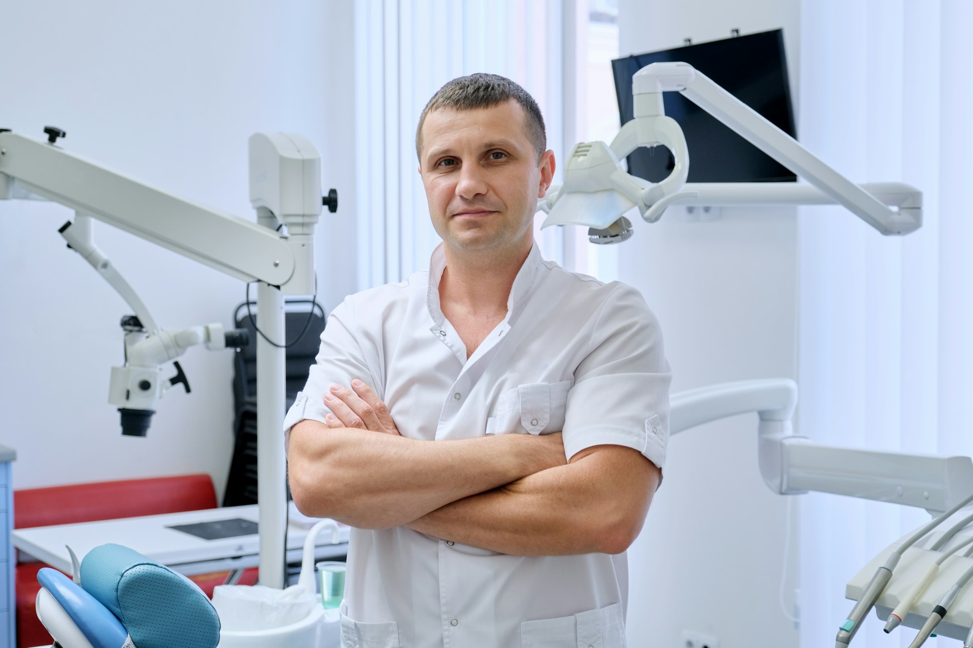 Portrait of confident friendly male dentist with crossed arms